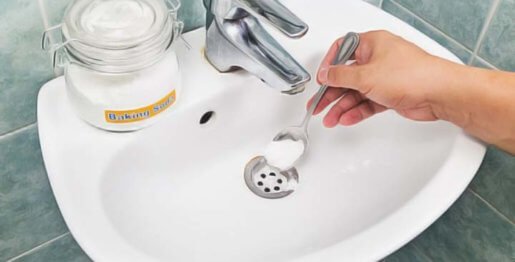 déboucher évier sans produit chimique : Main qui verse du bicarbonate de soude dans le lavabo
